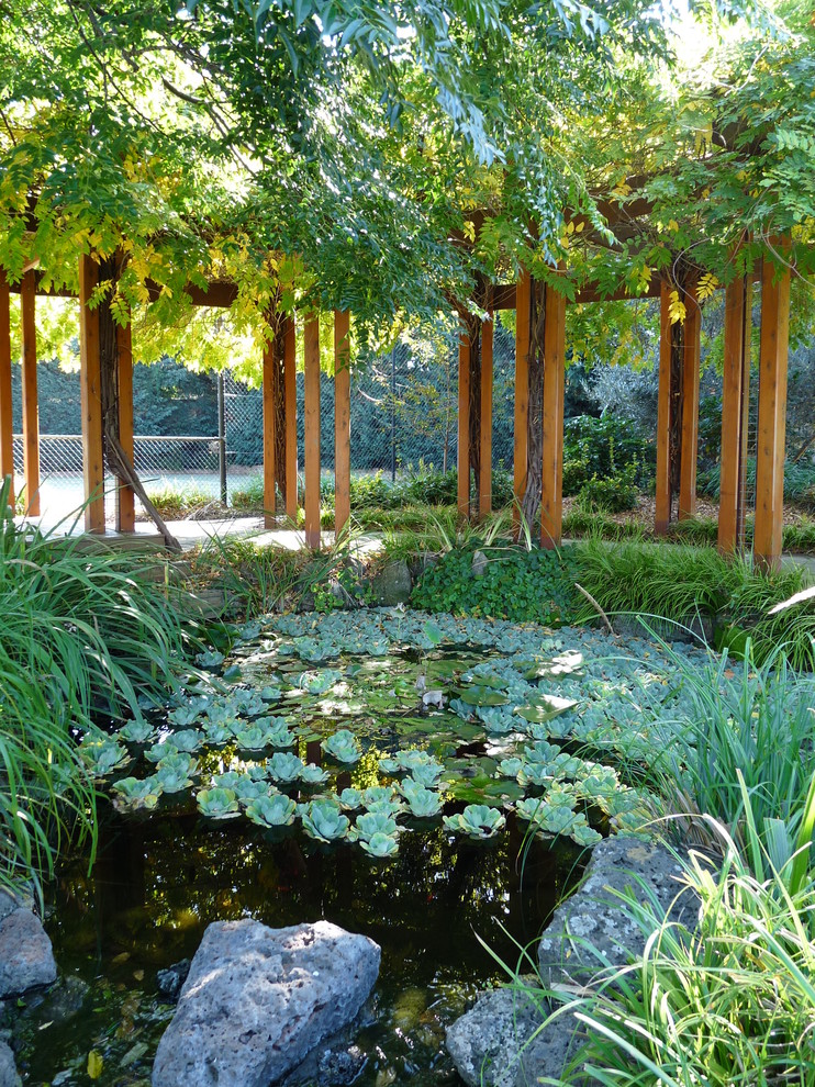 Large traditional backyard garden in Melbourne with a water feature.