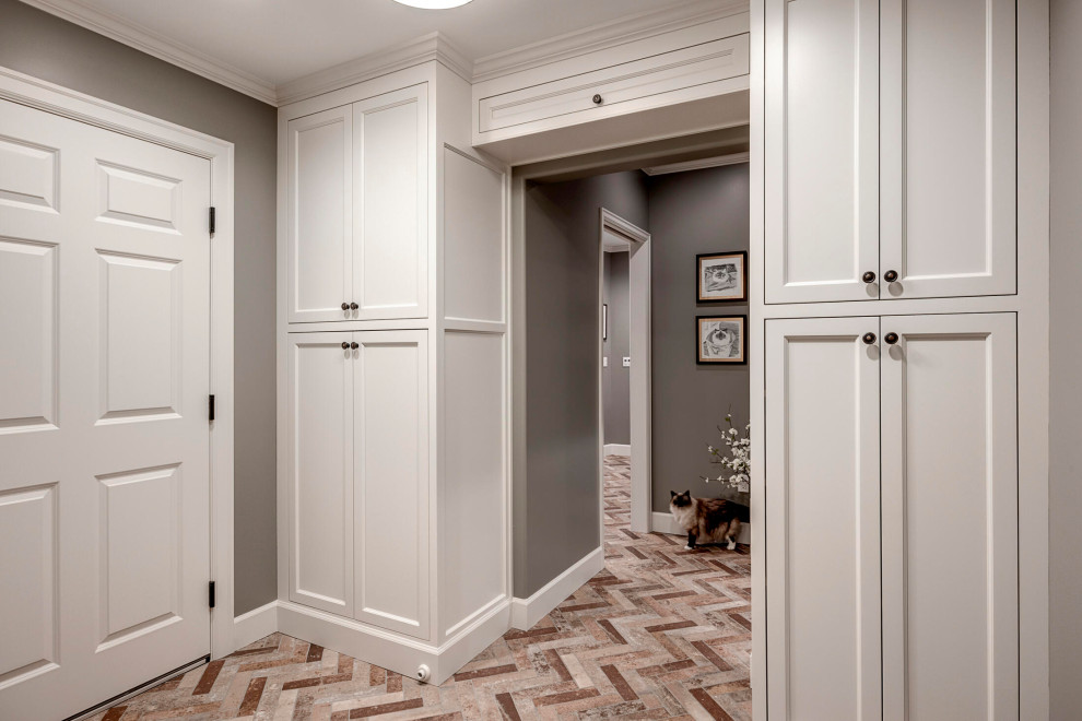 Exemple d'un petit couloir chic avec un mur gris, un sol en carrelage de porcelaine et un sol marron.
