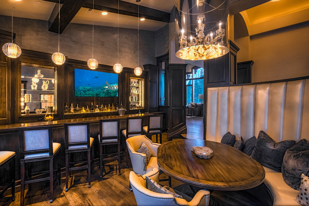 This is an example of an expansive transitional u-shaped seated home bar in Salt Lake City with dark wood cabinets, wood benchtops, brown splashback, mirror splashback, dark hardwood floors and brown floor.