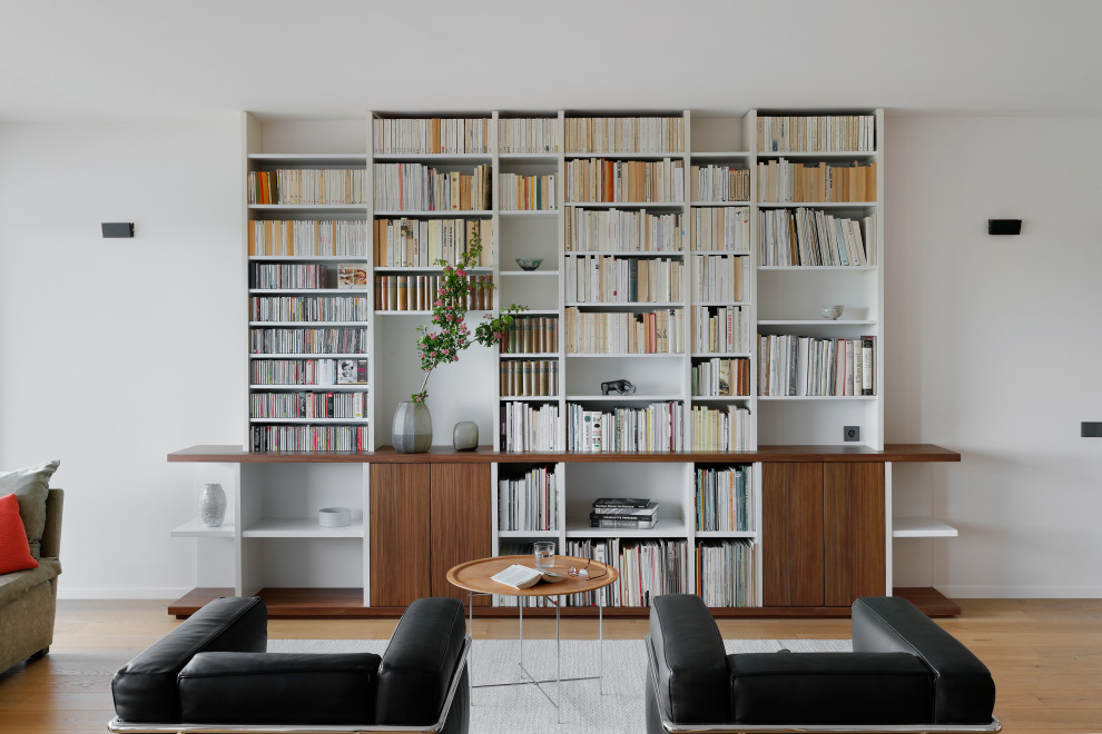 Esempio di un grande soggiorno moderno con libreria, pareti bianche, parquet chiaro, nessun camino e nessuna TV