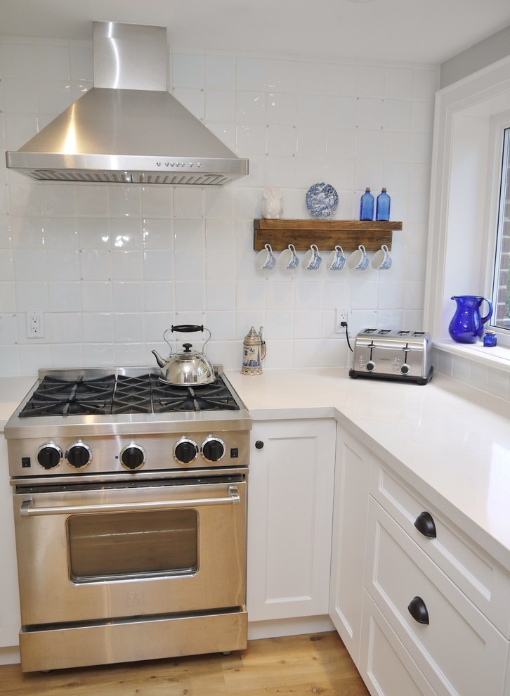 Eat-in kitchen - small transitional l-shaped light wood floor eat-in kitchen idea in Toronto with a farmhouse sink, shaker cabinets, white cabinets, quartz countertops, white backsplash, ceramic backsplash, stainless steel appliances and a peninsula