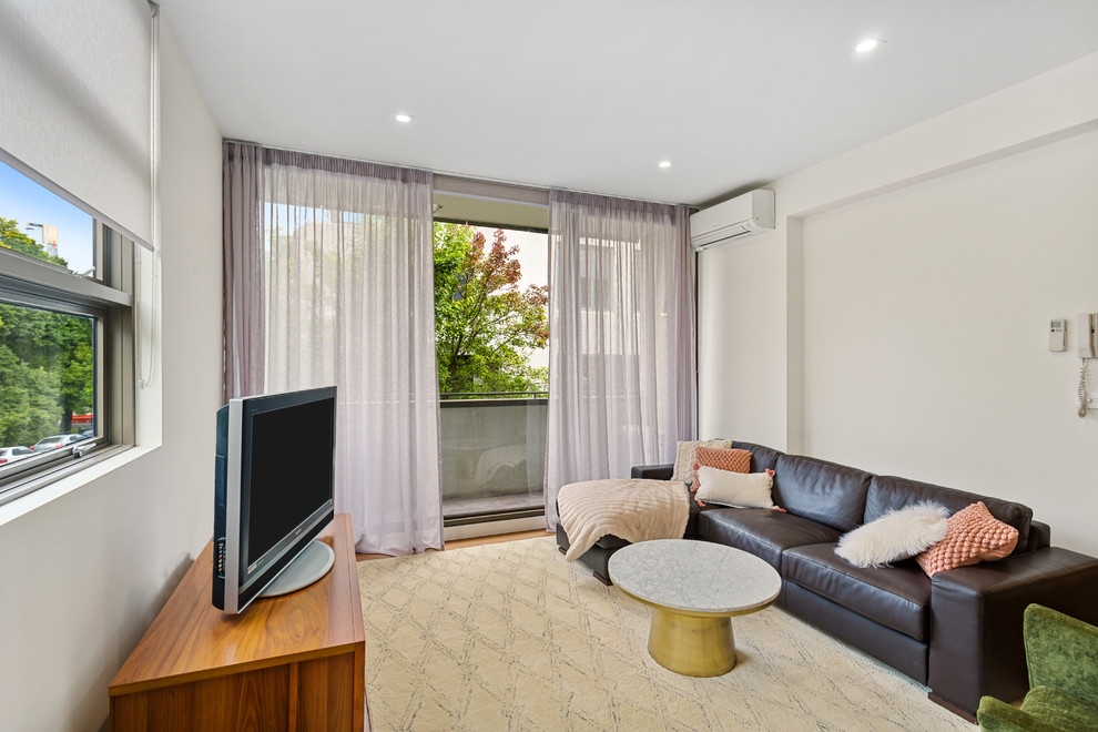 Medium sized contemporary open plan living room in Melbourne with white walls, medium hardwood flooring, a freestanding tv and brown floors.