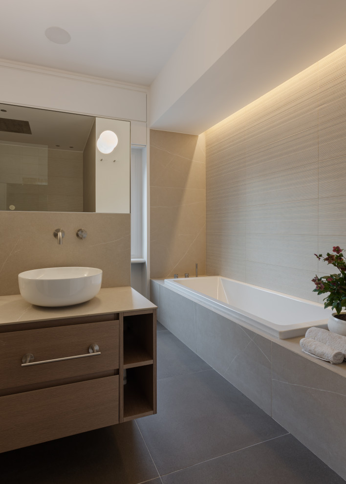 This is an example of a large contemporary master bathroom in Milan with flat-panel cabinets, grey cabinets, an alcove tub, a curbless shower, a two-piece toilet, beige tile, porcelain tile, grey walls, porcelain floors, a vessel sink, tile benchtops, brown floor, an open shower, grey benchtops, a shower seat, a double vanity and a floating vanity.