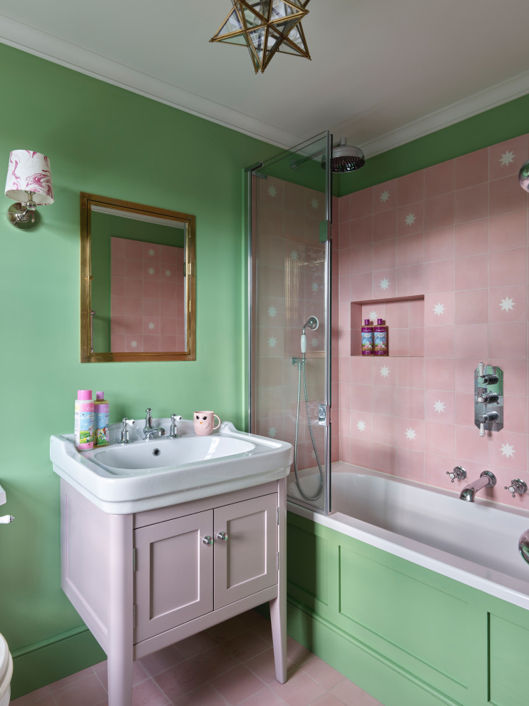 Inspiration for a small victorian family bathroom in London with green walls, ceramic flooring, pink floors, beaded cabinets, white cabinets, a corner bath, a shower/bath combination, a two-piece toilet, pink tiles, ceramic tiles, a console sink, a hinged door, a single sink and a freestanding vanity unit.