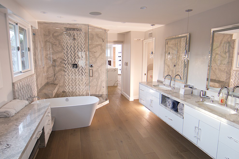 Photo of a large contemporary master bathroom in Orange County with flat-panel cabinets, white cabinets, a freestanding tub, a corner shower, multi-coloured tile, white tile, marble, white walls, light hardwood floors, an undermount sink, quartzite benchtops, beige floor, a hinged shower door and multi-coloured benchtops.
