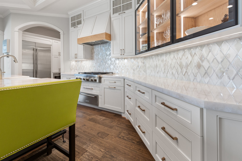 Inspiration for a large transitional single-wall light wood floor and brown floor eat-in kitchen remodel in Houston with a farmhouse sink, recessed-panel cabinets, white cabinets, quartzite countertops, white backsplash, mosaic tile backsplash, stainless steel appliances, an island and white countertops