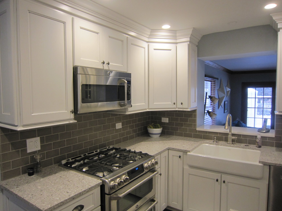 Inspiration for a mid-sized transitional medium tone wood floor eat-in kitchen remodel in Chicago with a farmhouse sink, recessed-panel cabinets, white cabinets, quartz countertops, gray backsplash, ceramic backsplash, stainless steel appliances and an island