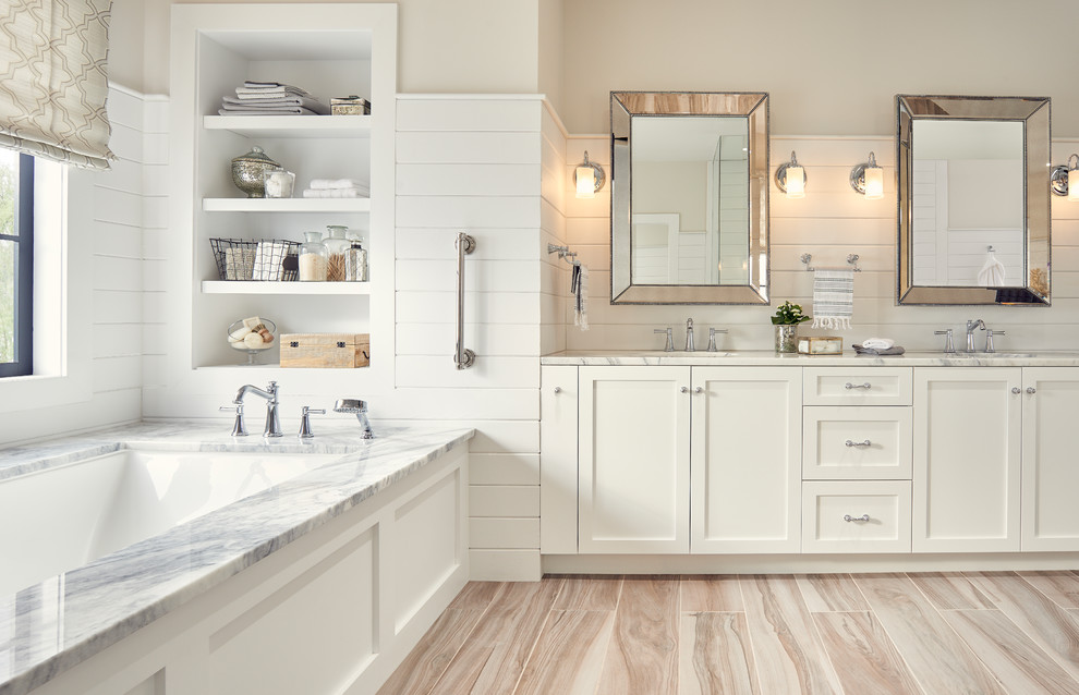 Inspiration for a large traditional master bathroom in Other with shaker cabinets, white cabinets, an undermount tub, white tile, marble benchtops, white walls, brown floor, an undermount sink and light hardwood floors.