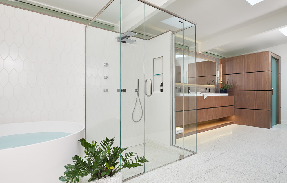 Photo of an expansive midcentury master bathroom in Grand Rapids with flat-panel cabinets, medium wood cabinets, a freestanding tub, a curbless shower, white walls, terrazzo floors, a trough sink, white floor and a hinged shower door.