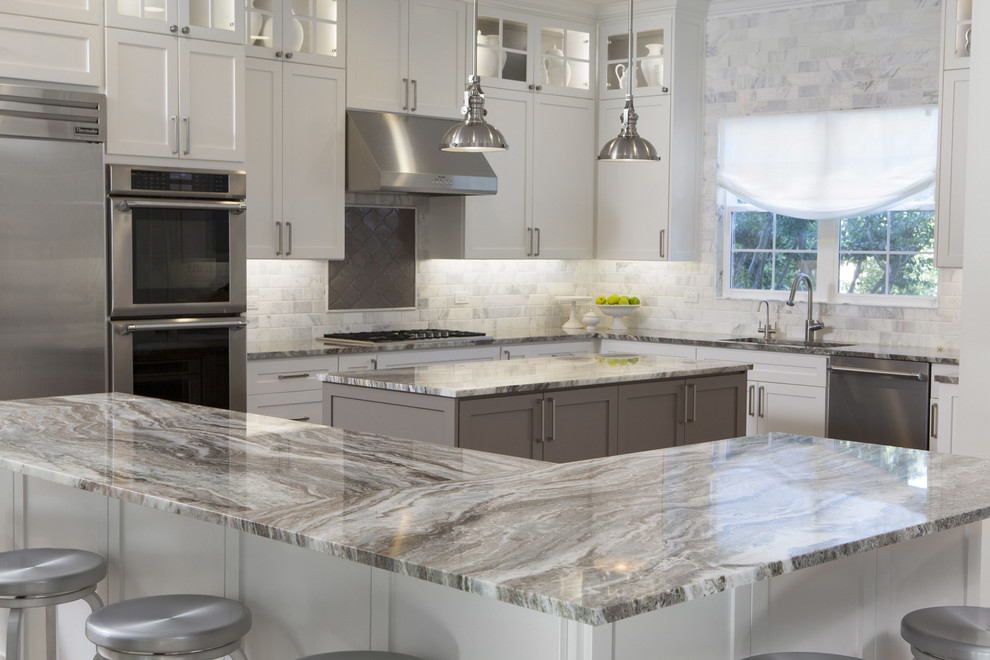 Inspiration for a mid-sized transitional u-shaped eat-in kitchen remodel in Austin with an undermount sink, shaker cabinets, white cabinets, marble countertops, white backsplash, porcelain backsplash, stainless steel appliances and an island