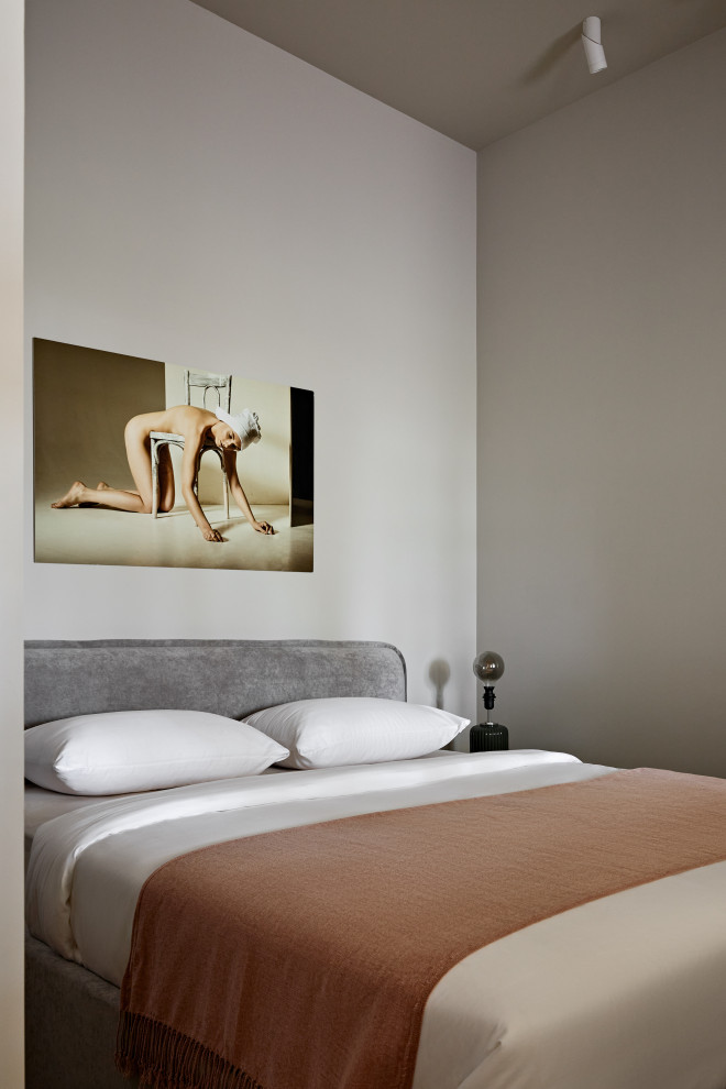 Immagine di una piccola camera da letto design con pareti beige, pavimento in legno massello medio e pavimento marrone