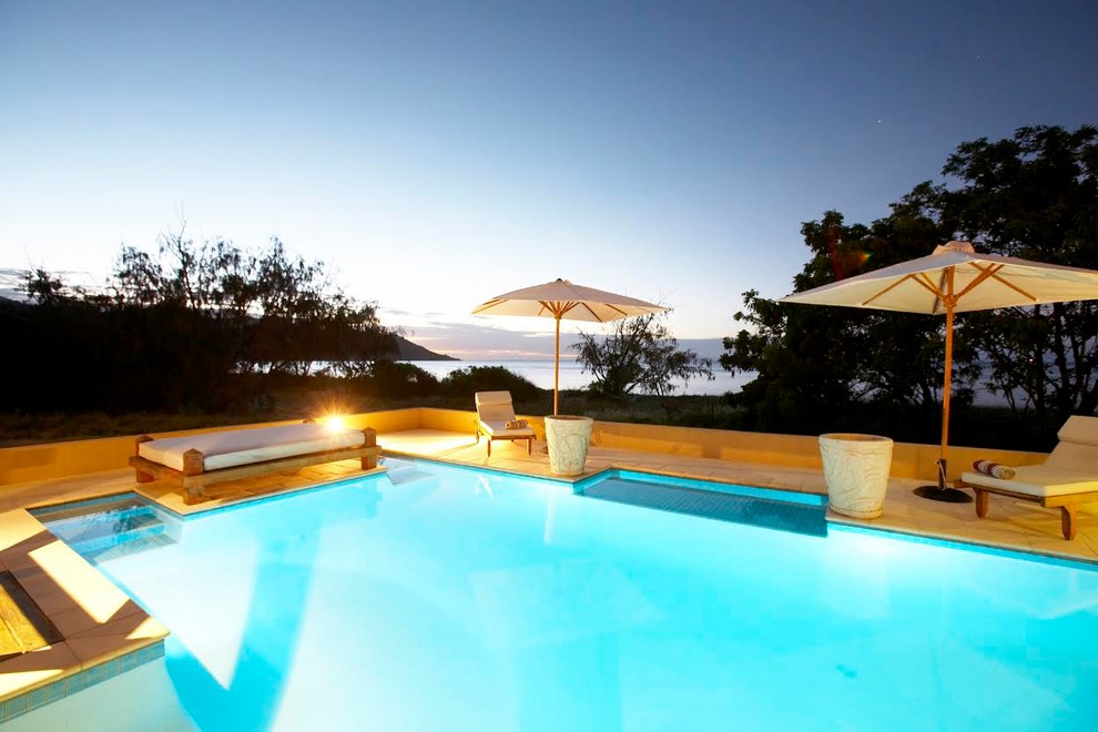 Inspiration for a large contemporary backyard custom-shaped pool in Townsville with natural stone pavers.