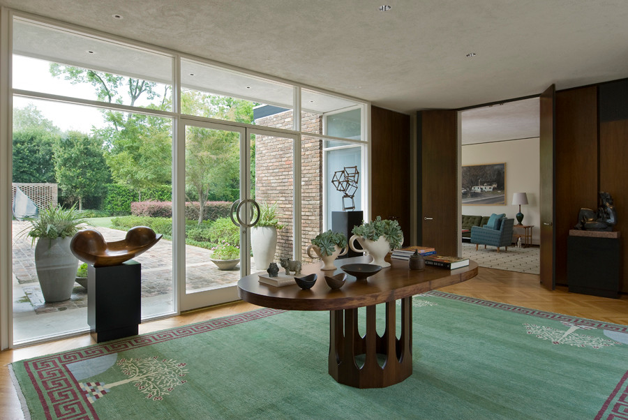 This is an example of a large midcentury foyer in Houston with brown walls, medium hardwood floors, a double front door, a glass front door and brown floor.