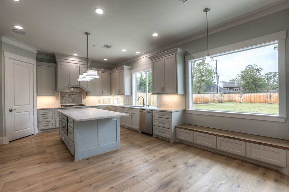 Inspiration for a mid-sized transitional u-shaped light wood floor and beige floor enclosed kitchen remodel in Houston with shaker cabinets, gray cabinets, white backsplash, stainless steel appliances, an island, a double-bowl sink, marble countertops and subway tile backsplash