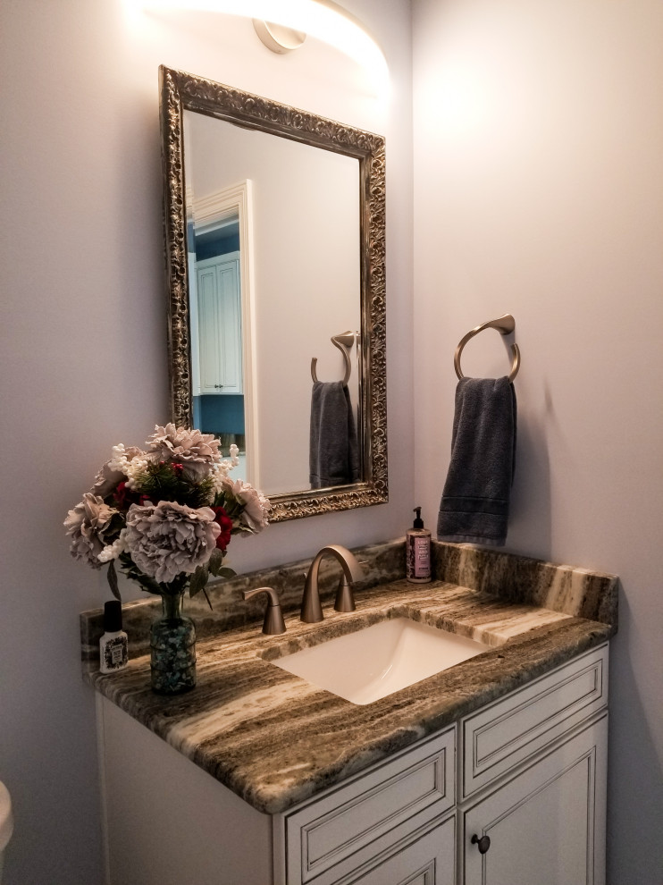 Inspiration for a small contemporary powder room in Cleveland with recessed-panel cabinets, beige cabinets, a one-piece toilet, grey walls, light hardwood floors, granite benchtops, grey floor, brown benchtops and a built-in vanity.