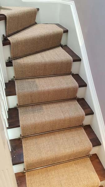 This is an example of a mid-sized country carpeted u-shaped staircase in London with carpet risers and wood railing.