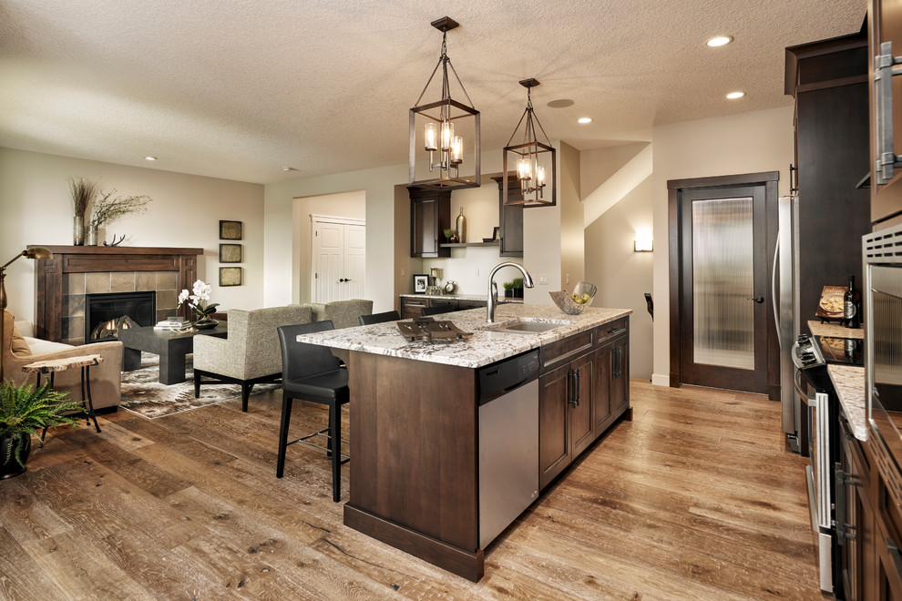 Inspiration for a transitional galley medium tone wood floor open concept kitchen remodel in Calgary with an undermount sink, recessed-panel cabinets, dark wood cabinets, quartz countertops, beige backsplash, stone tile backsplash, stainless steel appliances and an island
