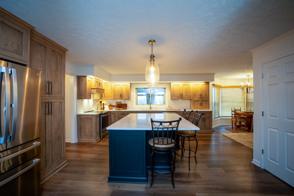 Eat-in kitchen - large transitional l-shaped medium tone wood floor and brown floor eat-in kitchen idea with a single-bowl sink, shaker cabinets, medium tone wood cabinets, quartz countertops, white backsplash, quartz backsplash, stainless steel appliances, an island and white countertops