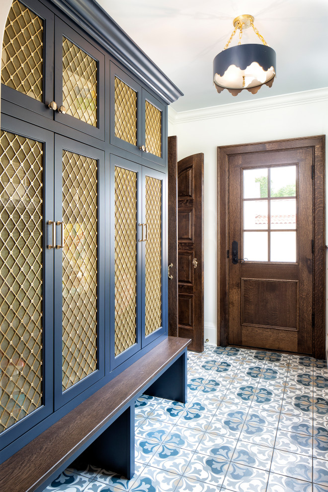 This is an example of a mediterranean mudroom in Minneapolis with white walls, ceramic floors, a brown front door and blue floor.