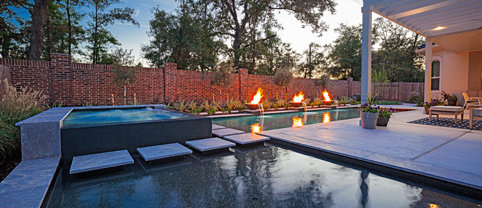 This is an example of a mid-sized contemporary backyard rectangular pool in Houston with a water feature and concrete slab.