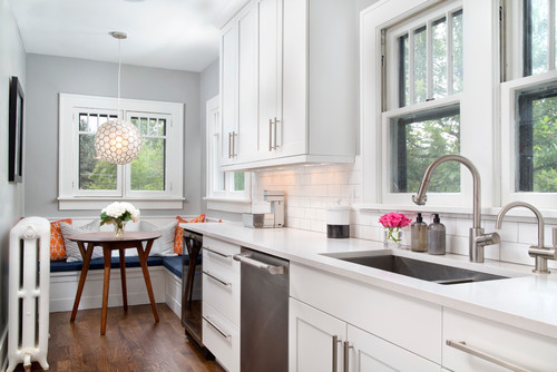 Durable, low-VOC white Shaker kitchen cabinets in Canada—galley layout with quartz counters, stainless dishwasher, and a cozy breakfast nook