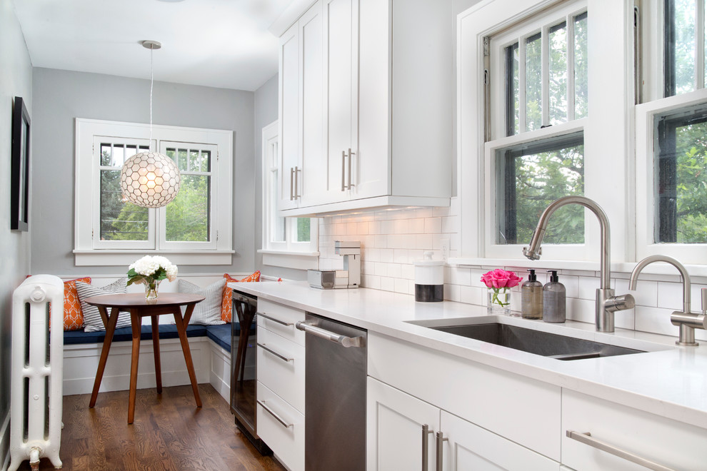 Example of a transitional dark wood floor eat-in kitchen design in Denver with an undermount sink, shaker cabinets, white cabinets, white backsplash, subway tile backsplash and stainless steel appliances