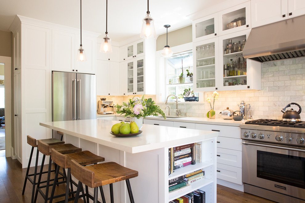 This is an example of a beach style l-shaped eat-in kitchen in San Francisco with an undermount sink, shaker cabinets, white cabinets, grey splashback, subway tile splashback, stainless steel appliances, medium hardwood floors, with island and brown floor.