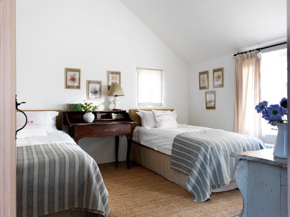 This is an example of a mid-sized traditional guest bedroom in London with white walls, carpet and brown floor.