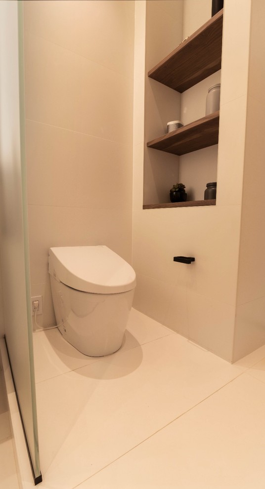 Modern bathroom in New York with flat-panel cabinets, white cabinets, a drop-in tub, an alcove shower, a one-piece toilet, white tile, porcelain tile, white walls, porcelain floors, an undermount sink, stainless steel benchtops, white floor, an open shower and black benchtops.