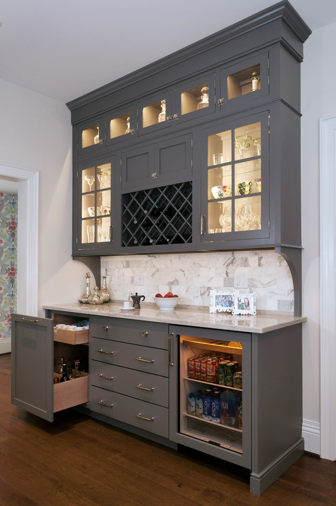 Photo of a traditional single-wall home bar in Other with glass-front cabinets, grey cabinets, quartzite benchtops, stone tile splashback, dark hardwood floors, no sink, multi-coloured splashback and brown floor.