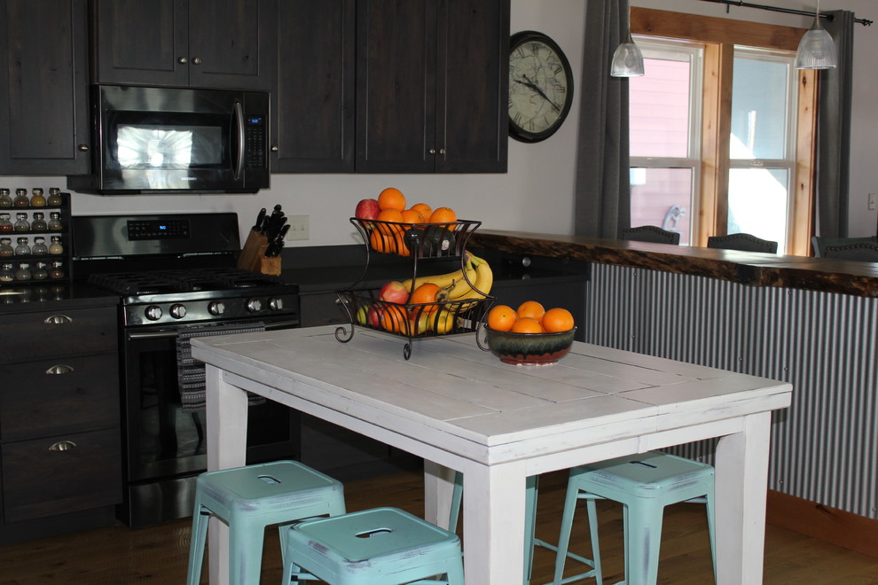 Example of a large transitional u-shaped light wood floor and brown floor open concept kitchen design with shaker cabinets, dark wood cabinets, an island and black countertops