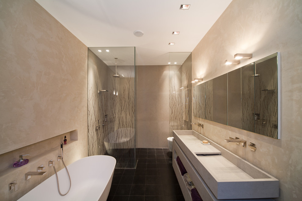 Contemporary bathroom in Cologne with open cabinets, grey cabinets, a freestanding tub, an open shower, black tile, ceramic floors, an integrated sink, concrete benchtops and an open shower.