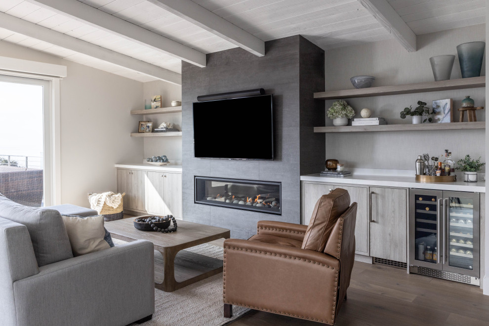 Photo of a mid-sized transitional open concept living room in San Francisco with a home bar, medium hardwood floors, a standard fireplace, a tile fireplace surround, a wall-mounted tv, brown floor and timber.