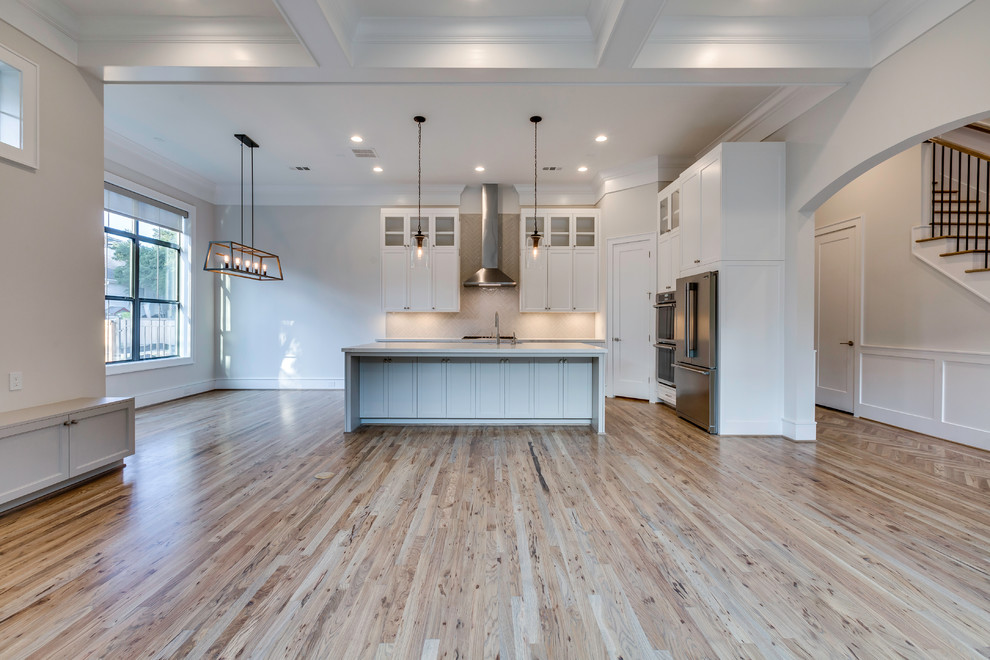 Eat-in kitchen - mid-sized transitional l-shaped light wood floor eat-in kitchen idea in Houston with shaker cabinets, white cabinets, stainless steel appliances, an island, white countertops, an undermount sink, gray backsplash and subway tile backsplash