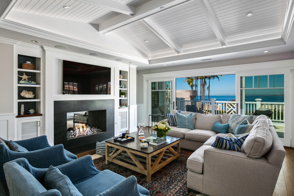 Стильный дизайн: гостиная комната в морском стиле с двусторонним камином и телевизором на стене - последний тренд