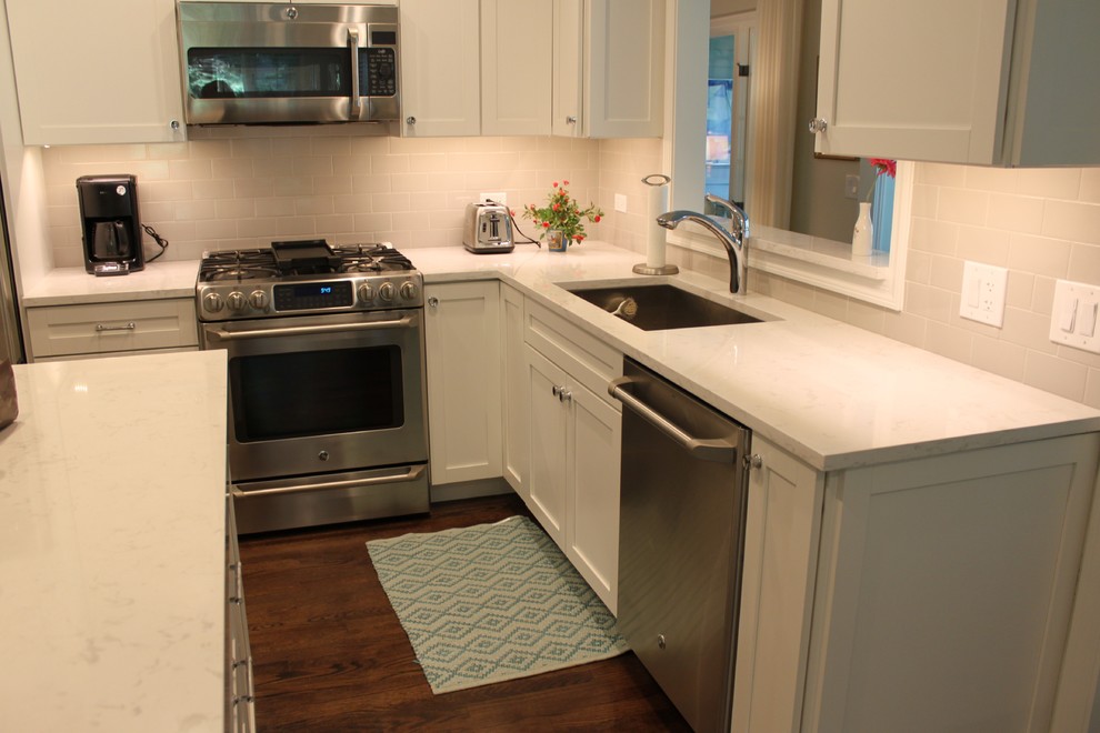 Inspiration for a mid-sized transitional l-shaped dark wood floor and brown floor enclosed kitchen remodel in Chicago with an undermount sink, recessed-panel cabinets, white cabinets, quartzite countertops, white backsplash, subway tile backsplash, stainless steel appliances and an island