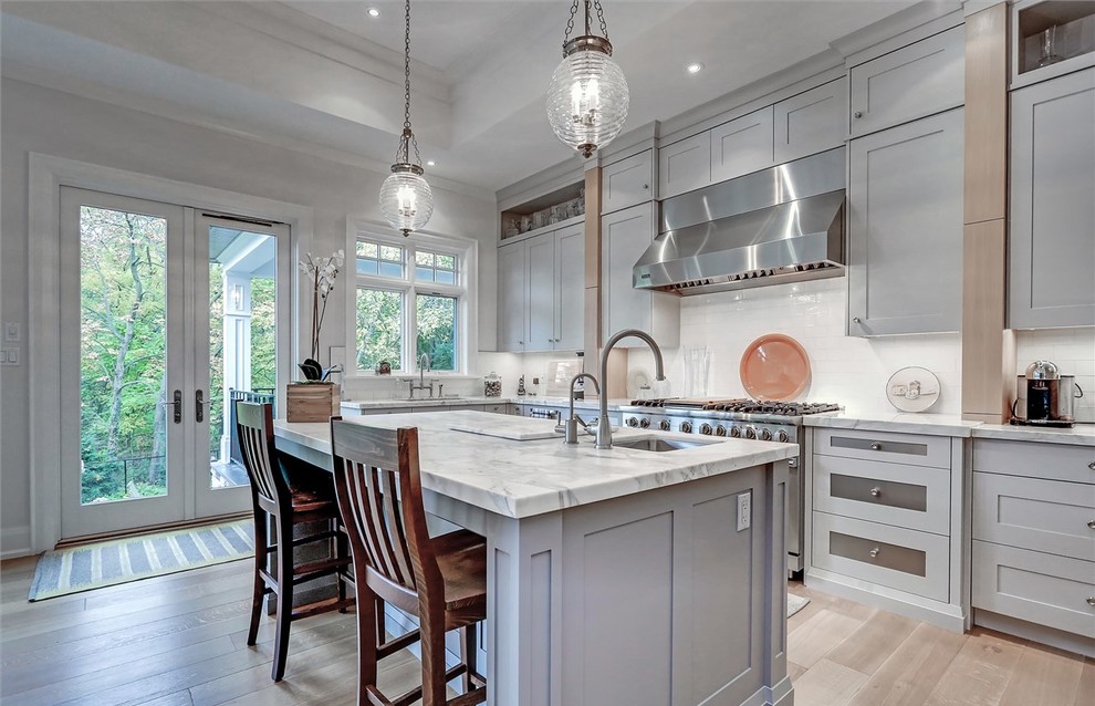 Inspiration for a transitional galley kitchen in Toronto with an undermount sink, shaker cabinets, grey cabinets, white splashback, stainless steel appliances, medium hardwood floors and with island.