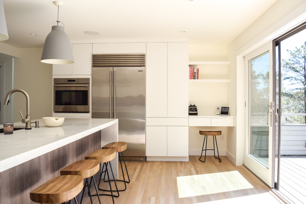 Inspiration for a large contemporary u-shaped eat-in kitchen in New York with an undermount sink, flat-panel cabinets, white cabinets, quartz benchtops, white splashback, stone slab splashback, stainless steel appliances, light hardwood floors, with island and white benchtop.