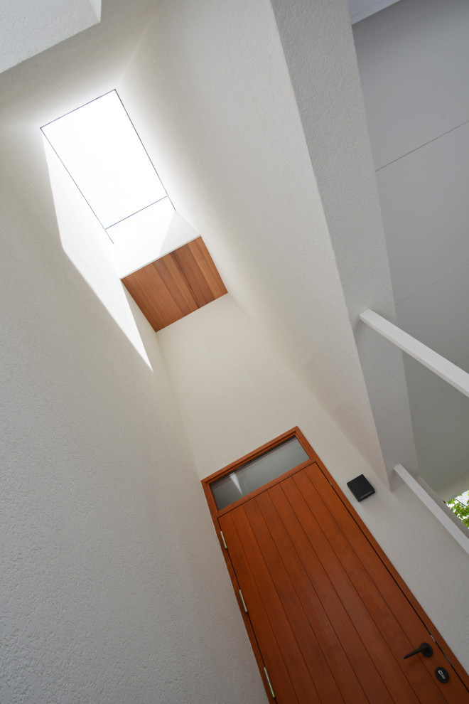 Foto di una porta d'ingresso minimalista con pareti bianche, pavimento in cemento, una porta singola, una porta in legno scuro, pavimento grigio e soffitto in perlinato