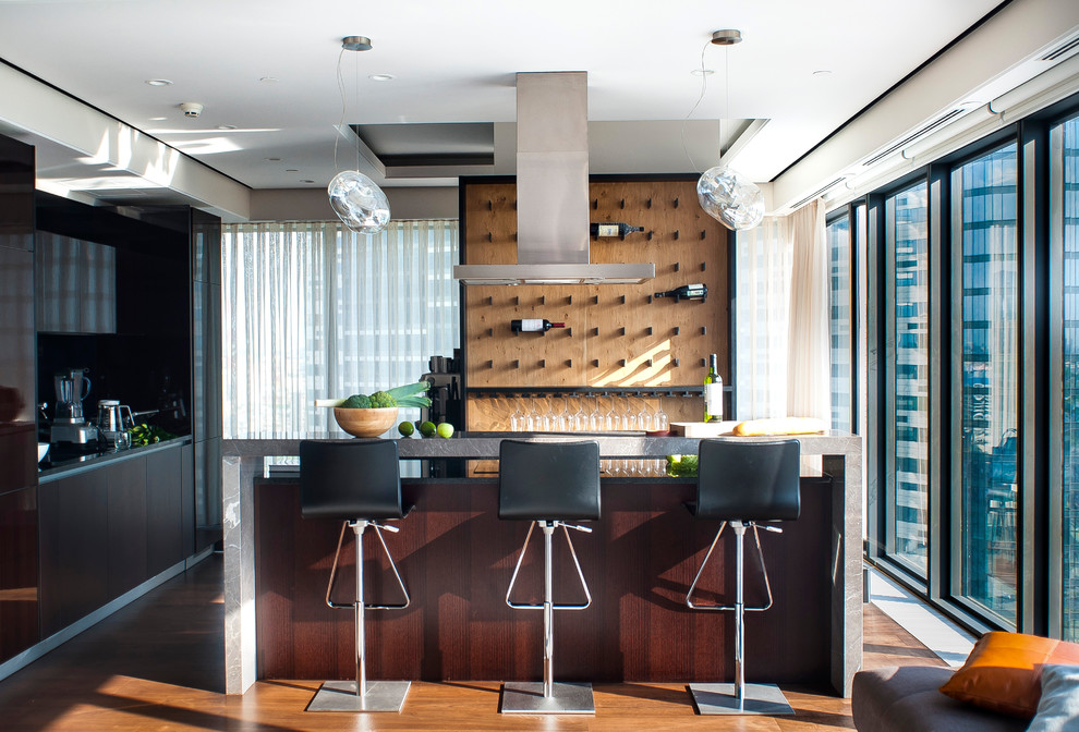 Photo of a contemporary l-shaped seated home bar in Moscow with flat-panel cabinets, dark wood cabinets, brown splashback, timber splashback, medium hardwood floors, brown floor and grey benchtop.