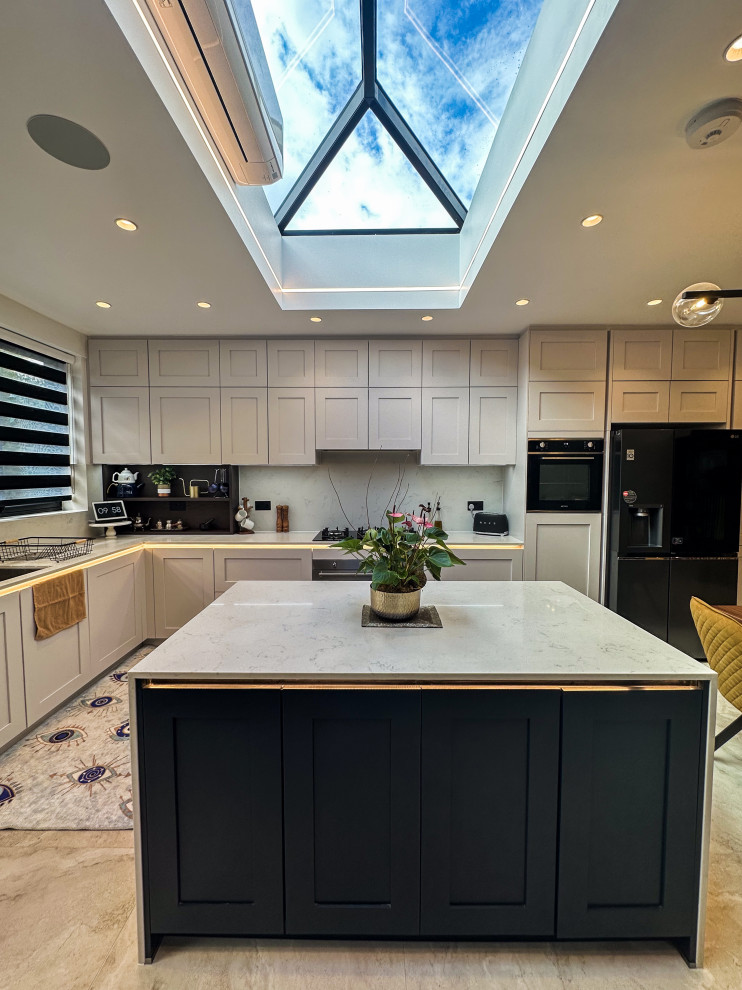 Large traditional l-shaped kitchen/diner in London with a built-in sink, shaker cabinets, blue cabinets, quartz worktops, white splashback, engineered quartz splashback, integrated appliances, porcelain flooring, an island, beige floors, white worktops and feature lighting.