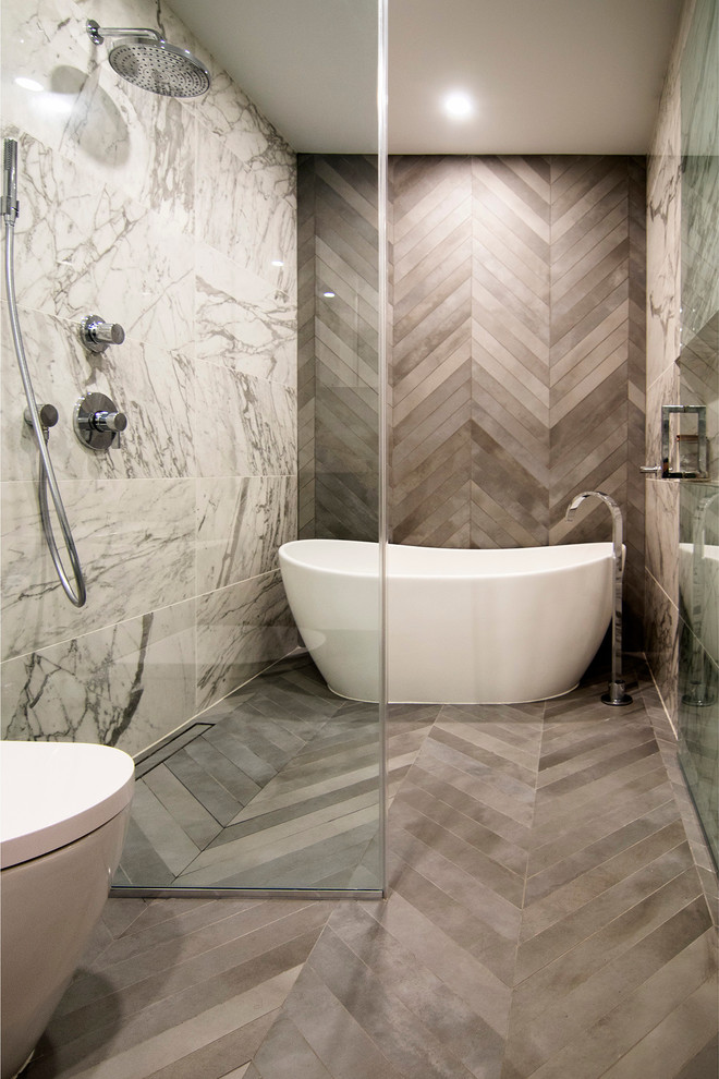 Photo of a mid-sized modern master wet room bathroom in New York with flat-panel cabinets, white cabinets, a freestanding tub, a two-piece toilet, black and white tile, porcelain tile, white walls, porcelain floors, an undermount sink, engineered quartz benchtops, grey floor, a hinged shower door and grey benchtops.