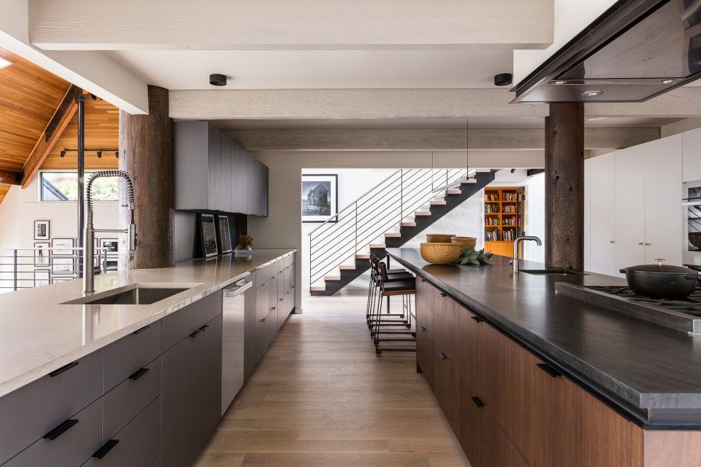 Inspiration for a contemporary kitchen in Seattle with an undermount sink, flat-panel cabinets, quartz benchtops, stainless steel appliances, light hardwood floors, with island, exposed beam, grey cabinets and white benchtop.