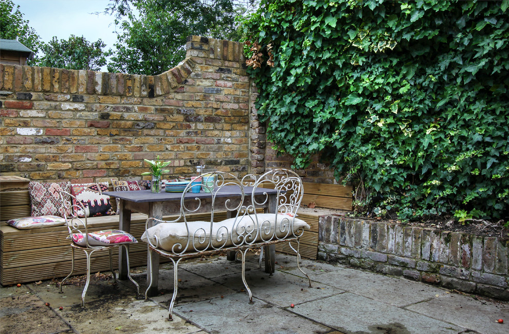Design ideas for a small traditional backyard patio in London with natural stone pavers.