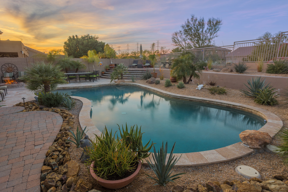 This is an example of a mid-sized mediterranean backyard custom-shaped pool in Phoenix with gravel.