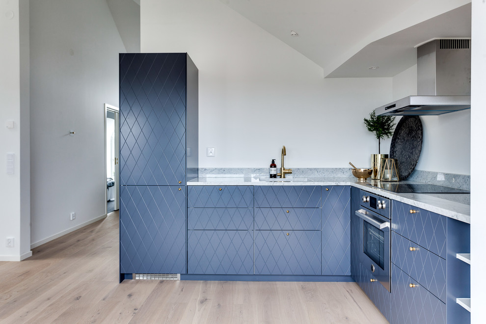 Mid-sized scandinavian l-shaped kitchen in Stockholm with a single-bowl sink, blue cabinets, marble benchtops, stainless steel appliances, light hardwood floors and no island.