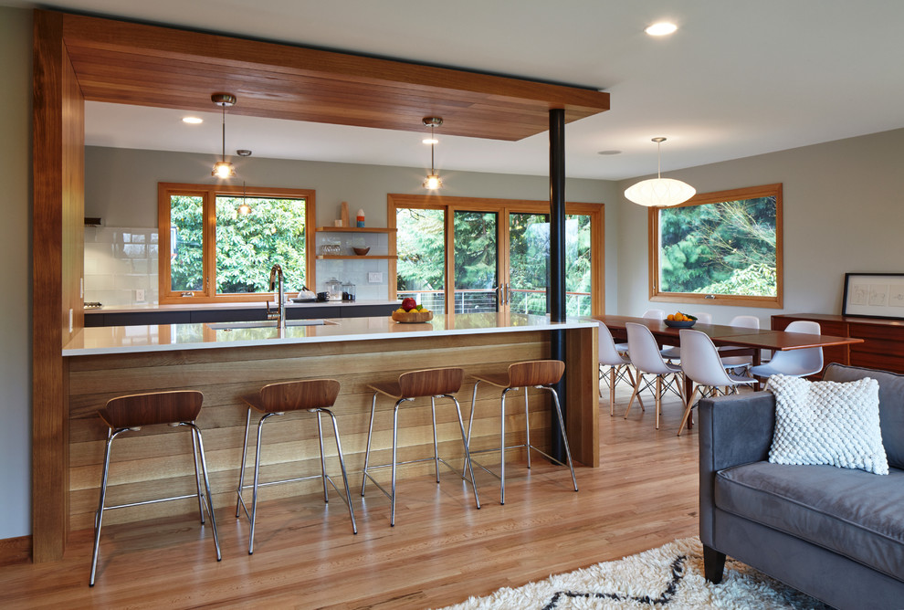 Inspiration for a midcentury galley eat-in kitchen in Portland with a drop-in sink, flat-panel cabinets, grey cabinets, quartz benchtops, white splashback, glass tile splashback, stainless steel appliances, medium hardwood floors and a peninsula.