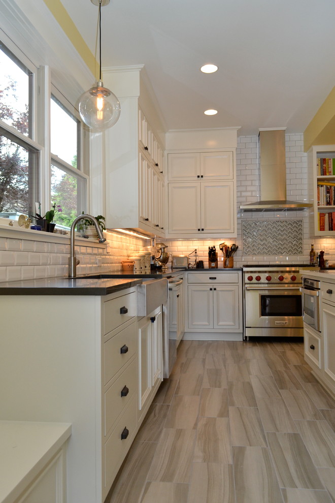 Photo of a large traditional u-shaped separate kitchen in Portland with a farmhouse sink, white cabinets, white splashback, subway tile splashback, stainless steel appliances, with island, recessed-panel cabinets, quartz benchtops and porcelain floors.