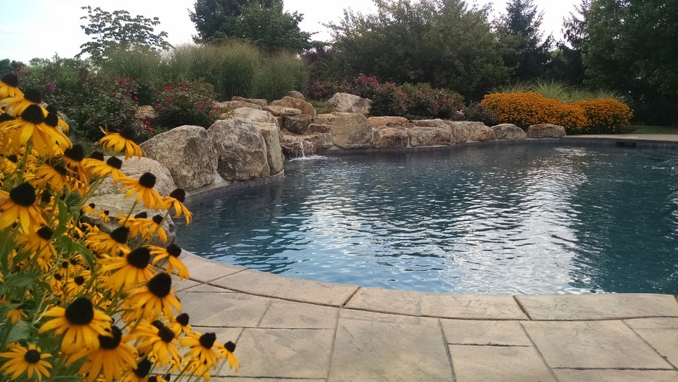Large mountain style backyard custom-shaped and stamped concrete natural pool photo in New York