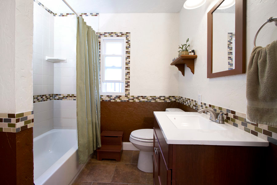 Inspiration for a mid-sized traditional bathroom in Denver with shaker cabinets, dark wood cabinets, an alcove tub, a shower/bathtub combo, a two-piece toilet, white tile, porcelain tile, white walls, porcelain floors, an integrated sink, solid surface benchtops, brown floor and a shower curtain.